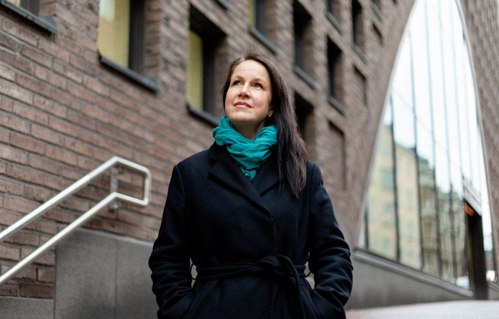 Honkasalo seisoo Helsingin yliopiston kirjaston edessä, katsoo taivaalle.
